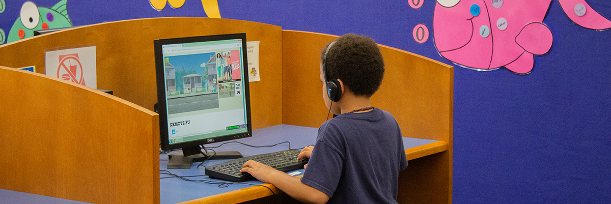 Young boy using desktop computer in library