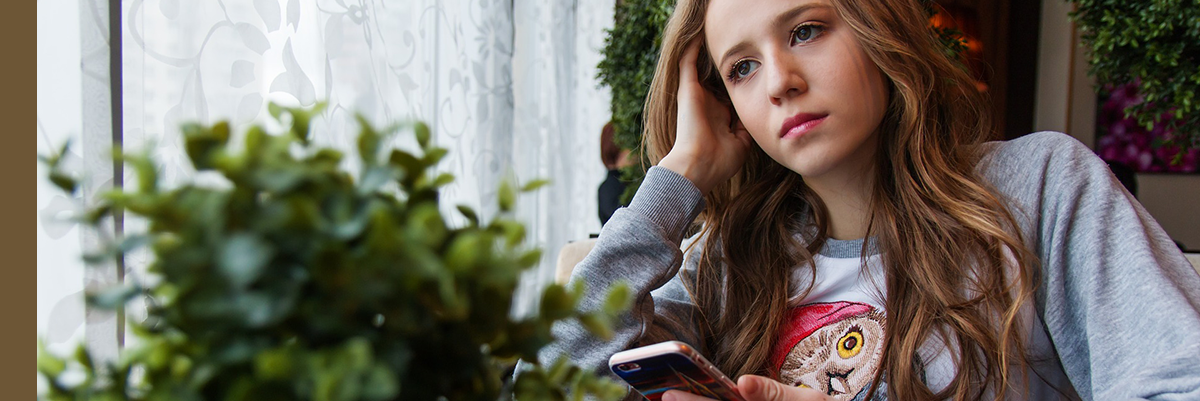 Young teen looking worried with phone in her hand