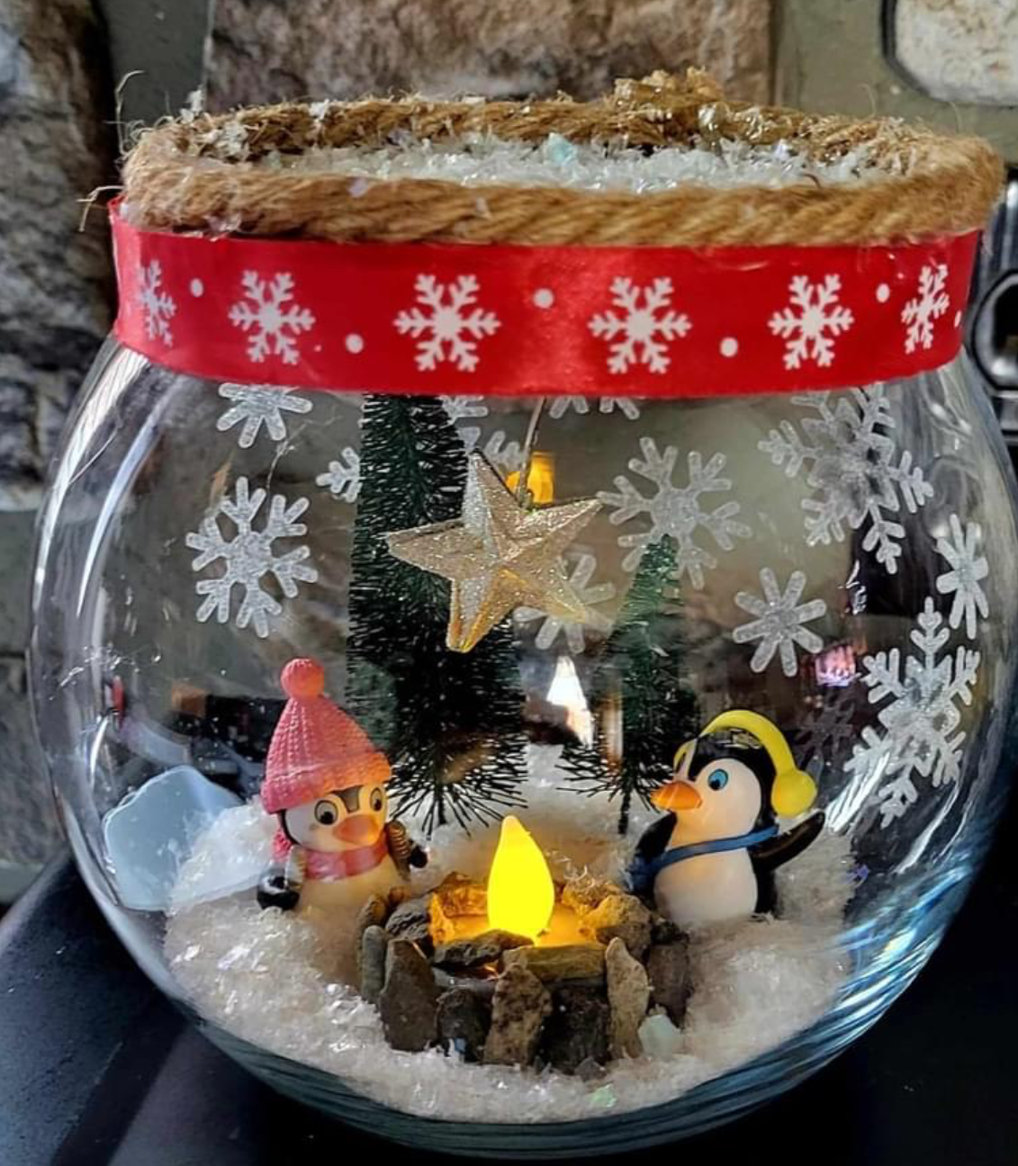 penguins in a glass jar with a faux fire and fake snow