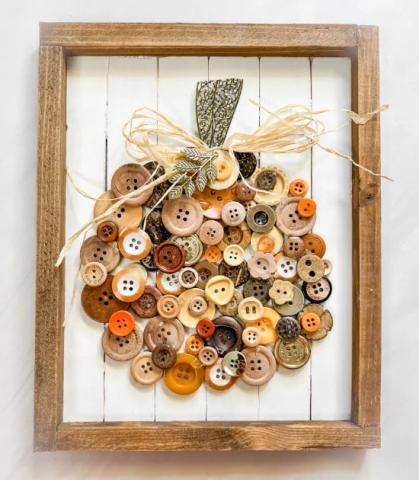 Photo of a pumpkin-shaped art piece made of buttons inside a wooden frame.