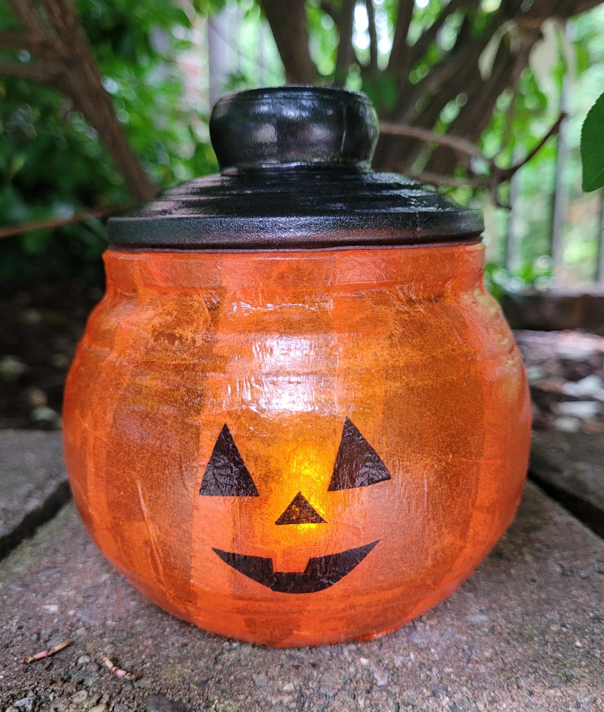 round jar with lid decoupaged and painted to resemble a jack-o-lantern